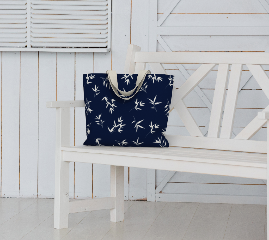 White bamboo leaves in a tossed repeat on a Navy background. Market Tote Bag sitting on white bench seat.