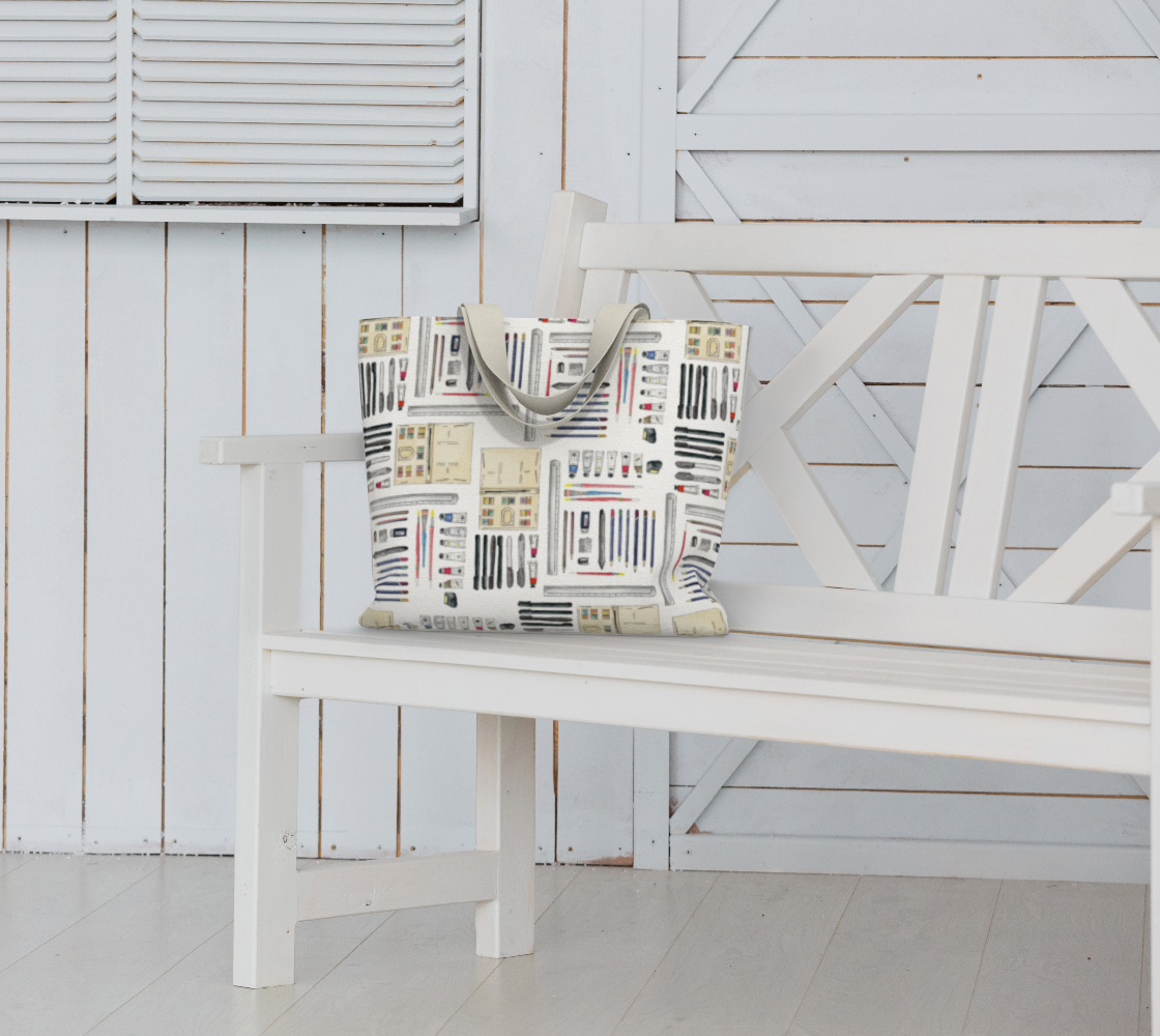 Art Supplies in a repeating pattern on a white background. Large market tote bag with white cotton canvas handles. Bag sitting on a white garden bench seat.